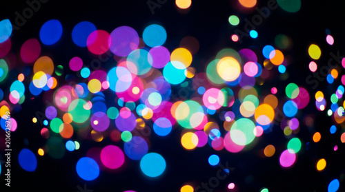 Multicolored circular bokeh lights glowing against a deep black background creating a festive atmosphere for holiday celebrations and artistic designs