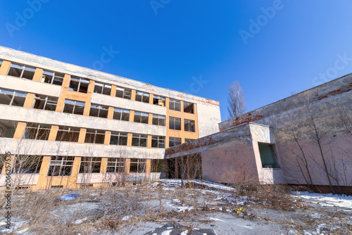 Tableau sur toile Abandoned and dilapidated communist era school building with broken windows under a clear blue sky
