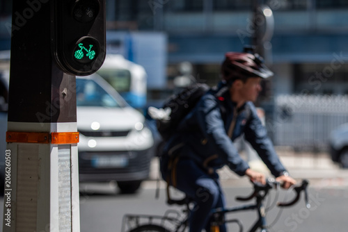 Foto Green bicycle traffic light signal with cyclist in background, Paris