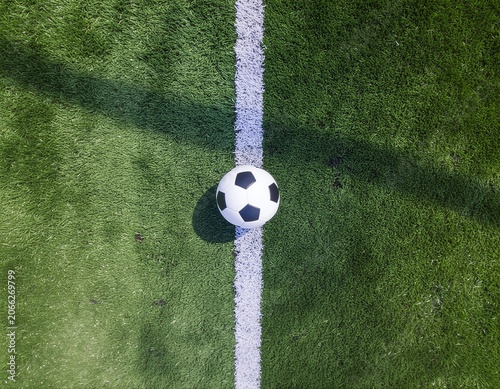 Soccer ball centered on a white field line on an artificial turf pitch with a top-down perspective
