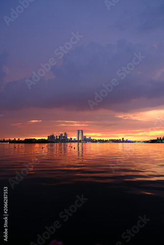 Φωτογραφία City skyline over calm water at sunset