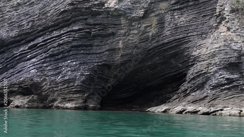 Dramatic layered coastal cliffs rising above turquoise sea in Hat Khanom–Mu Ko Thale Tai National Park. Geological rock formations shaped by millions of years of erosion.