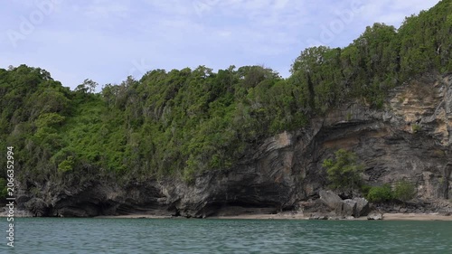Lush limestone cliffs overlooking crystal-clear turquoise sea in Hat Khanom–Mu Ko Thale Tai National Park. Scenic tropical coastline and protected natural landscape.