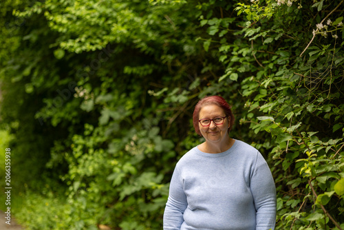 Mature woman smiling wearing glasses outdoors in nature