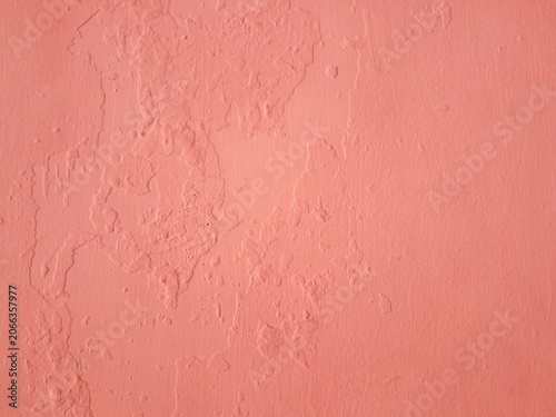 Pink concrete wall background with abstract cracked texture of damaged and weathered cement surface.