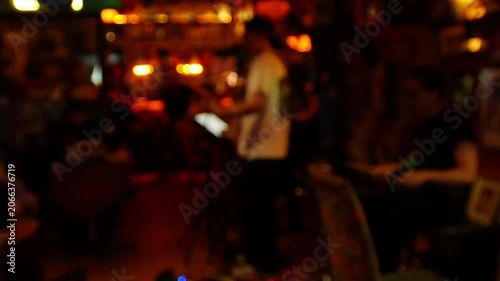 Blurred defocused live music band performance inside dark moody bar with warm amber bokeh lights and crowd audience nightlife
