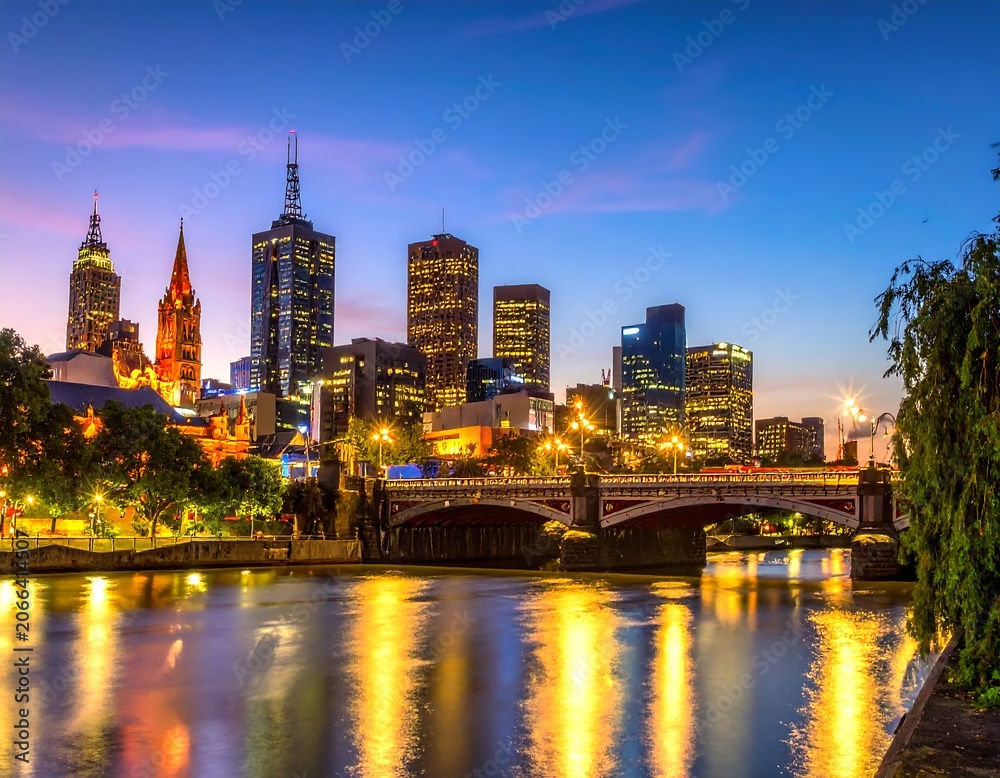 Obraz premium Cityscape skyline at dusk with bridge and river reflection