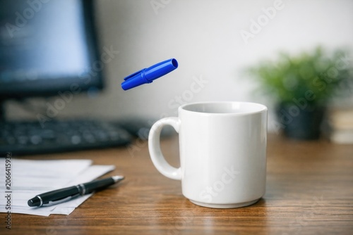 A coffee cup with a pen stuck in it, perfect for office or home use