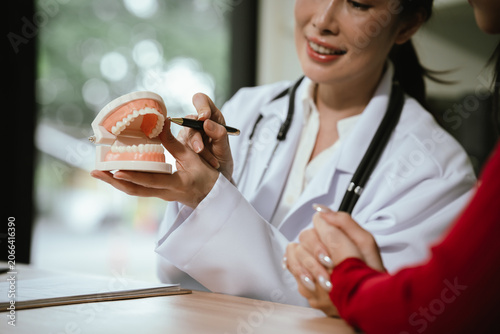 Fotografía Female dentist consulting with a patient in a modern dental clinic, holding a te