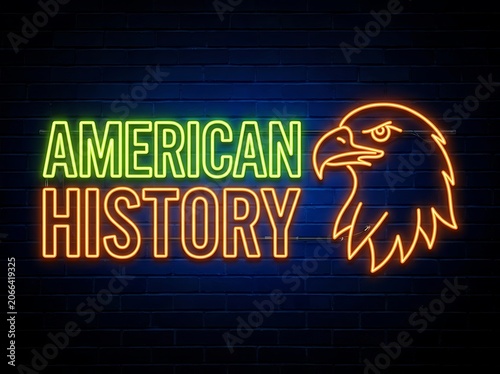 Neon sign with the text american history and a bald eagle icon on a dark blue brick wall background