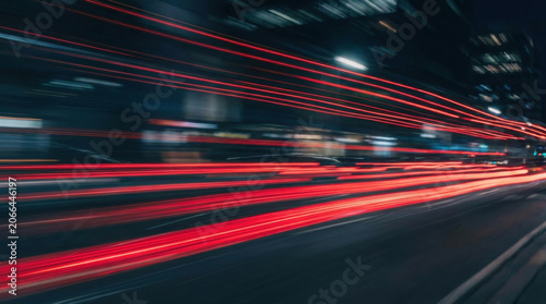 Light trail night city street traffic motion blur Long exposure light trail night urban street with fast traffic motion blur, red streak line across road, dynamic speed and energy, modern city