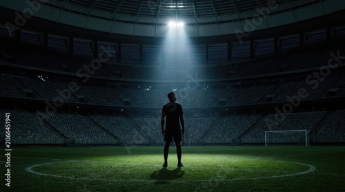 Soccer Player Silhouette Standing Under Stadium Spotlight at Night