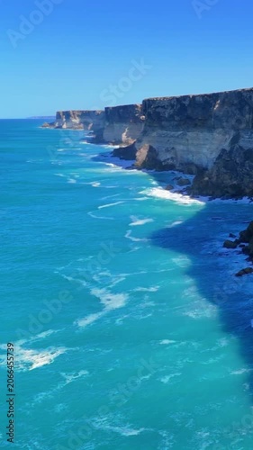 4K vertical drone footage approaching Australia’s Bunda Cliffs from offshore, showing blue sea, white surf, and layered vertical cliffs