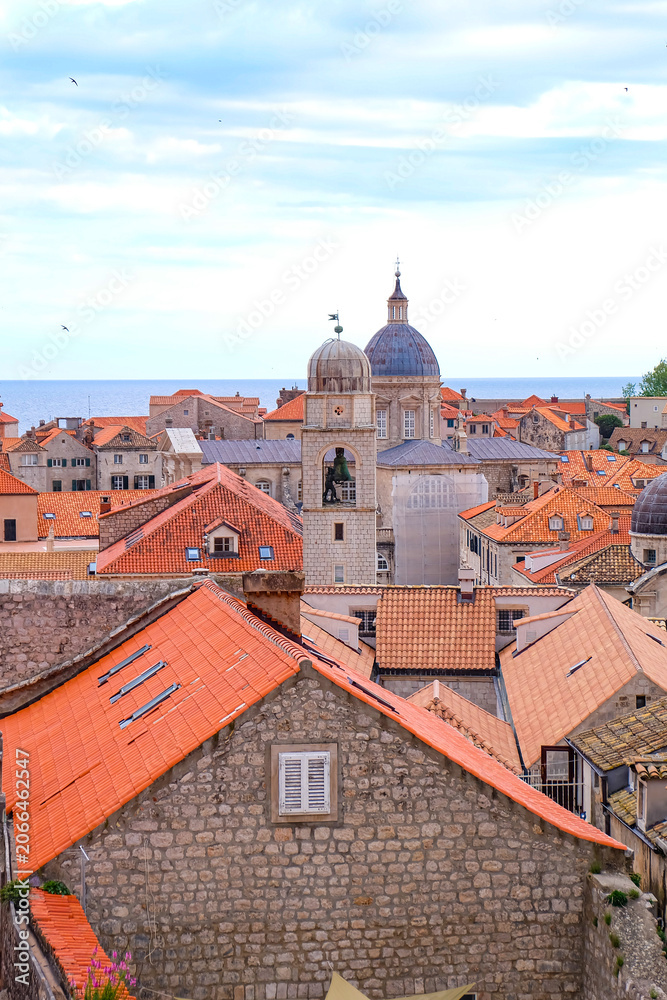 Obraz premium Aerial and above view of Dubrovnik old town with the Bell and Clock Tower and the red orange tiled roof surrounded by the city wall, Croatia 