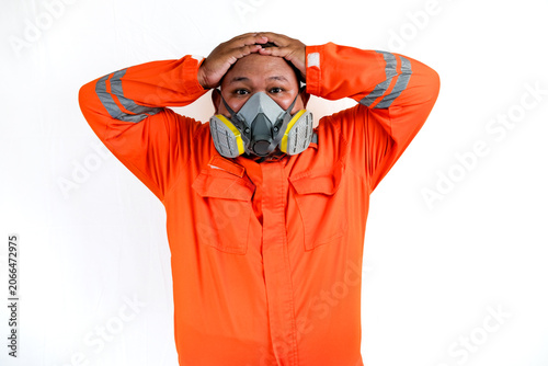 Fotografie Young Adult Worker grips head, wearing orange safety gear and respirator mask ag