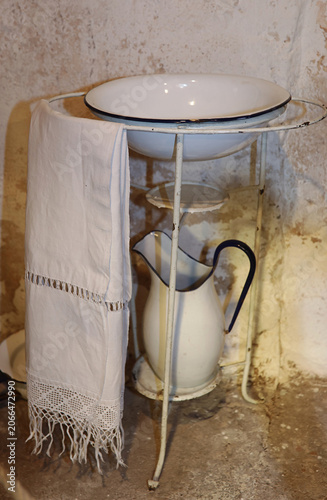Canvas Print Vintage enamel washstand with basin pitcher and embroidered towel in a rustic co
