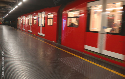 Red subway train in motion at Milan metro station platform in Italy