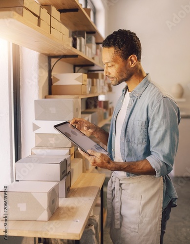 Man using tablet in small business packaging workshop