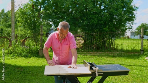 Professional Woodworker Using Table Saw in Garden Workshop