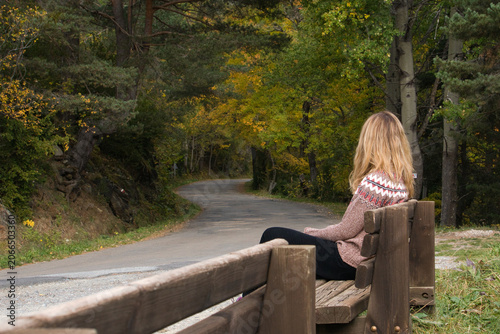 Young woman contemplating autumn nature on a forest bench