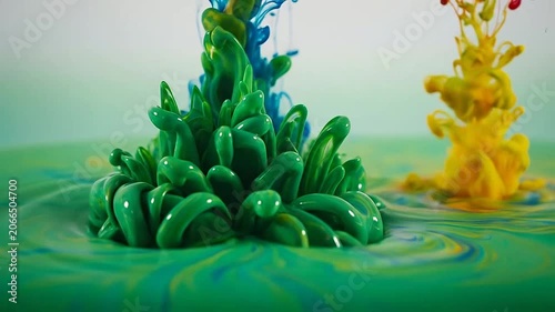 Abstract macro shot of vibrant green and yellow paint splashing in liquid