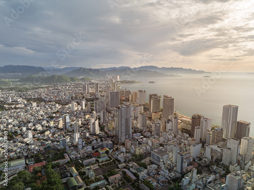 Aerial view of Nha Trang city skyline and beachfront district under soft morning light with mountains and South China Sea horizon.