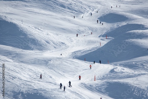Skiers Descending a Snowy Mountain Slope on a Sunny Day.