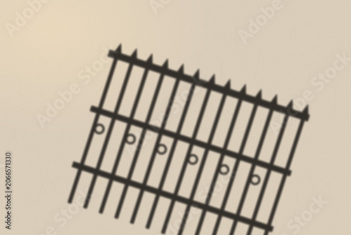 Illuminated Shadows of the City – Iron Fence Shadow on Textured Wall
