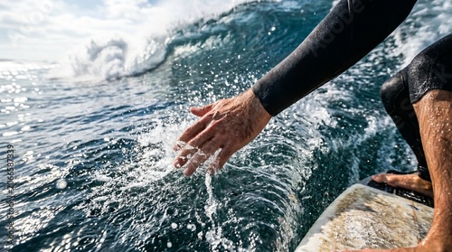 Surfer reaching out towards wave while balancing on surfboard in the ocean  