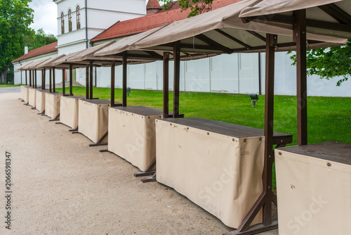 Row of covered market stalls waiting for vendors and customers in an outdoor marketplace. Suitable for retail, commerce, local economy and seasonal market concepts.