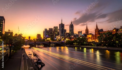 Glowing Urban Skyline Reflecting on River at Sunset with Light Trails