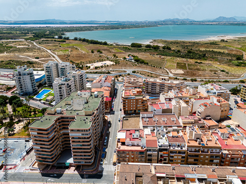Aerial view of coastal resort town with buildings, roads, and Laguna Salada de la Mata. Travel and tourism destination concept for real estate and vacation. Costa Blanca, Spain