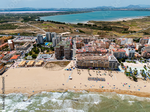 Aerial view of coastal La Mata town with sandy beaches, apartment buildings, and Mediterranean sea. Tourism, real estate development, and summer vacation concept for travel. Costa Blanca, Spain