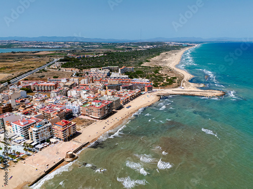 Aerial view spanish coastal town with sandy beaches, residential buildings, and Mediterranean Sea. Coastal tourism and vacation destination concept for travel advertising. La Mata, Costa Blanca, Spain