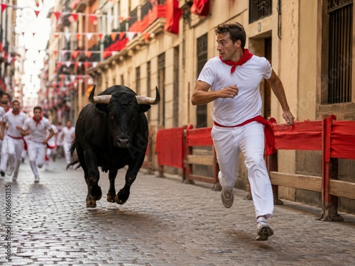 White-clad runner chased by bull on cobblestone street