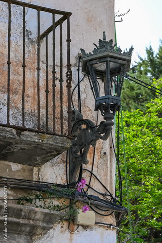 traditional wrought iron street lantern mounted beside an aged balcony in Ronda, Andalusia, Spain