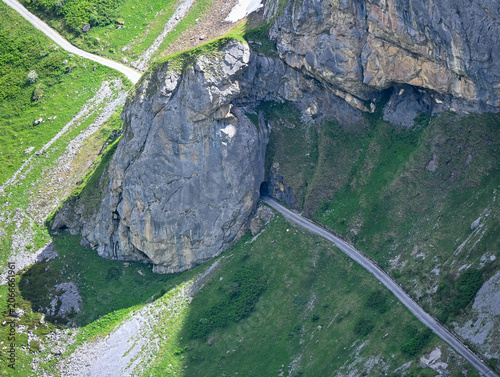 path into a tunnel carved through a rocky cliff near Klausen Pass, Switzerland