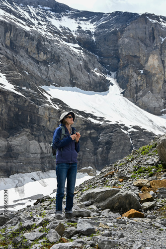 A lone hiker traverses a rugged field of rocks and glacial debris near Klausen Pass in the Swiss Alps