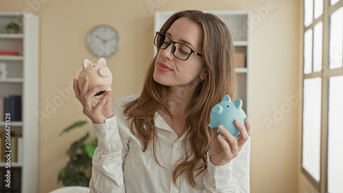 Foto Woman comparing pink and blue piggy banks, holding both and inspecting slots, bare hands visible in building; savings choice thoughtful