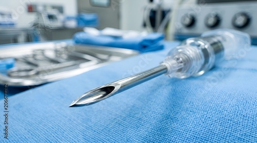 Close-up of surgical needle and sterile medical equipment on blue cloth