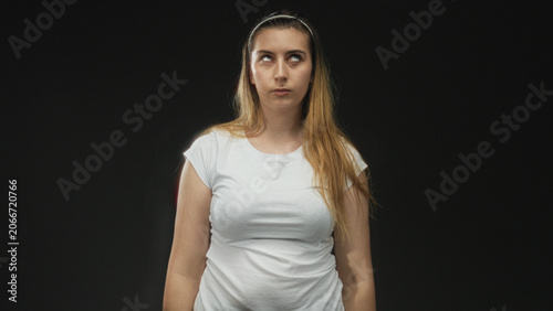 Photography Woman rolling eyes in studio wearing white tshirt and headband, standing with unimpressed stare; annoyance silent critique