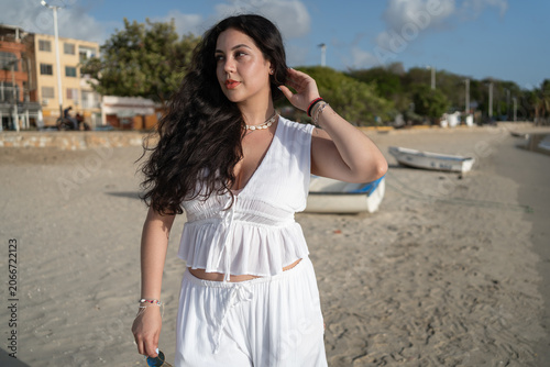 Tableau sur toile La bonita joven está paseando con su outfit blanco en las arenas de la playa en la Isla de Margarita
