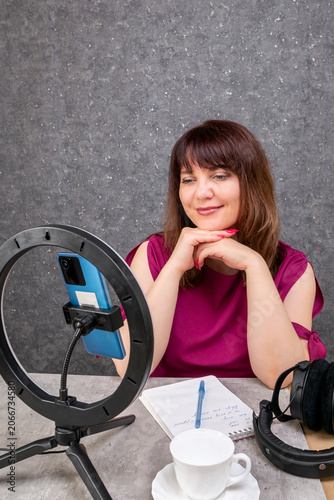 A young female blogger broadcasts live from her smartphone at home.