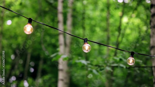 Light bulbs hang on a wire decorating the patio. Shooting in motion
