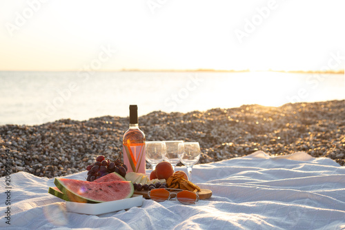 Konstfotografi Aesthetic summer picnic for three friends layout on a pebble beach during sunset