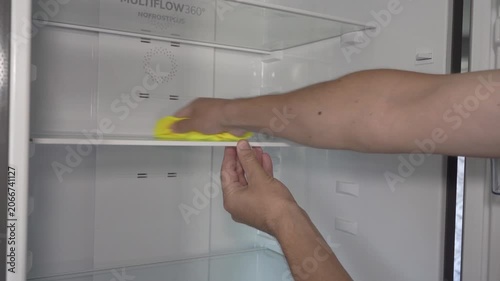 Cleaning modern refrigerator at home, Man washing glass shelf inside empty fridge close up