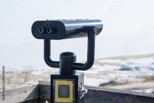 Viewing telescope mounted on wooden deck provides a view of the sandy beach and water of the Curonian Spit in the distance