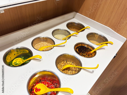Картината върху платно A hot pot condiment bar with a wide variety of sauces, spices, and toppings neatly arranged for diners to customize their meals