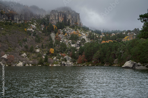 Laguna Negra glacial lake in Natural Park of Laguna Negra and Circos Glaciares de Urbion, Soria, Spain, surrounded by granite cliffs and pine forest under an overcast sky