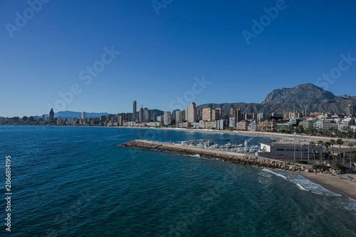 View of Benidorm skyline and marina with palm trees and Mediterranean coast in Alicante, Spain.